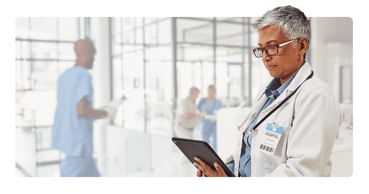 Doctor Reviewing Patient Notes on Tablet – AIEMM Medical Transcription Mature female doctor using tablet to document patient care in a modern hospital